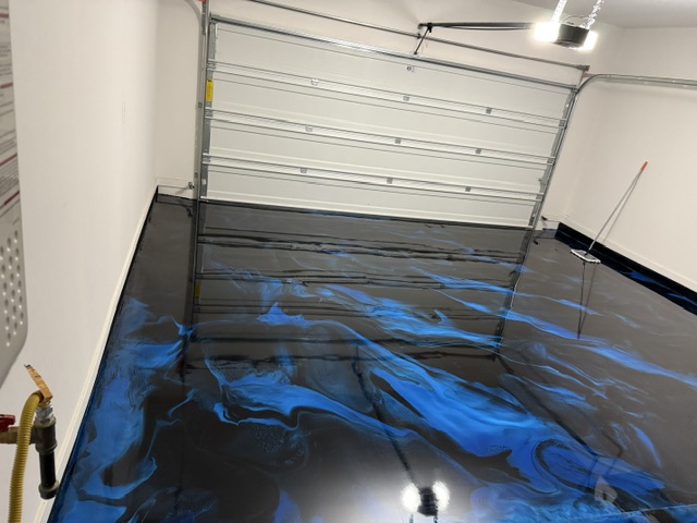 Blue and black metallic swirl epoxy floor in a residential garage with overhead door open