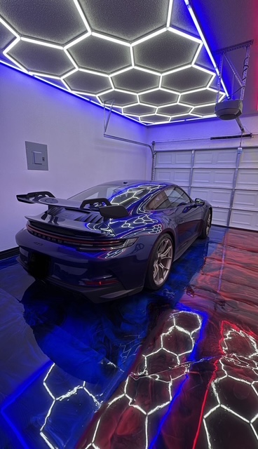 Porsche 911 GT3 on a custom blue and black metallic epoxy garage floor with hex LED ceiling lighting