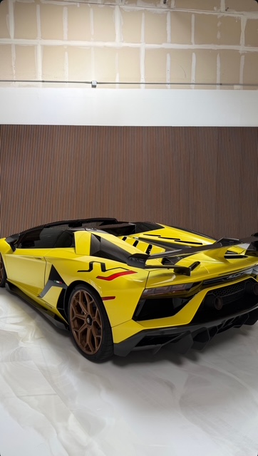 Yellow Lamborghini Aventador SVJ in a private showroom on a polished white epoxy floor